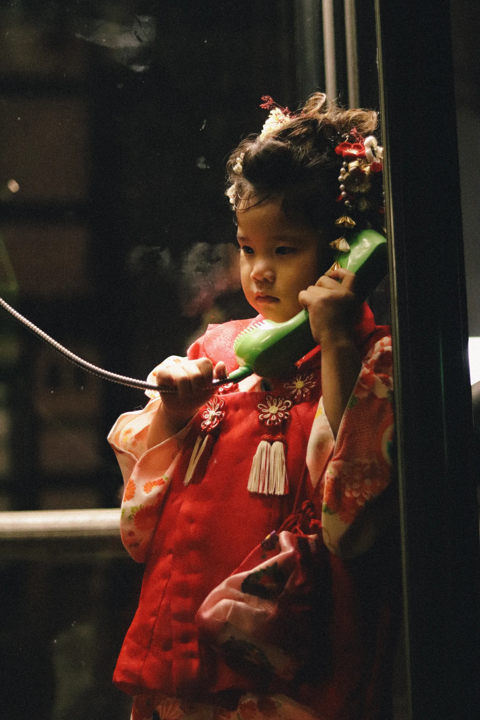 Kind in kimono in een telefooncel